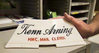 A paper weight that reads Kenn Arning, Mail Clerk