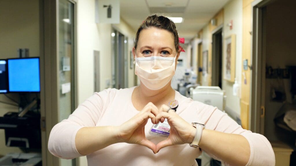 Heart Institute employee makes hand heart