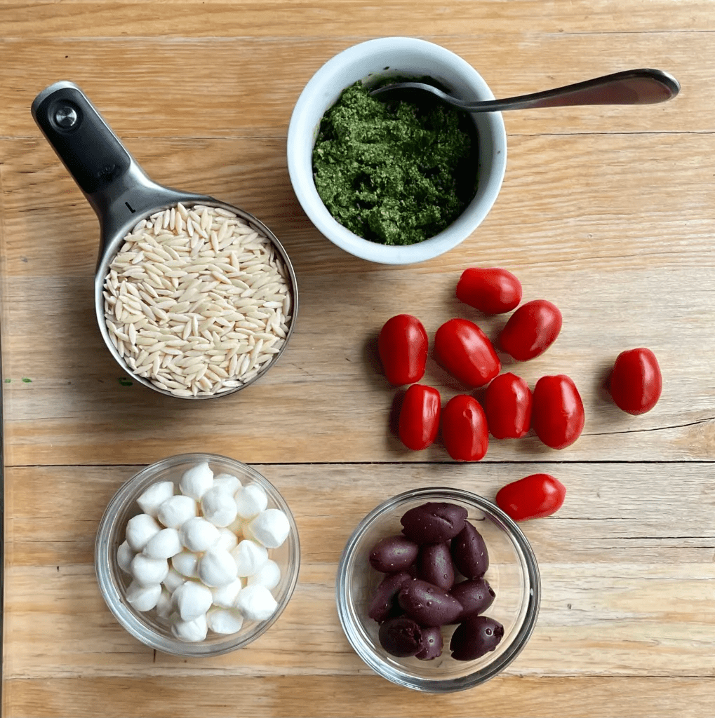 Various ingredients shown on a countertop to make a pesto salad