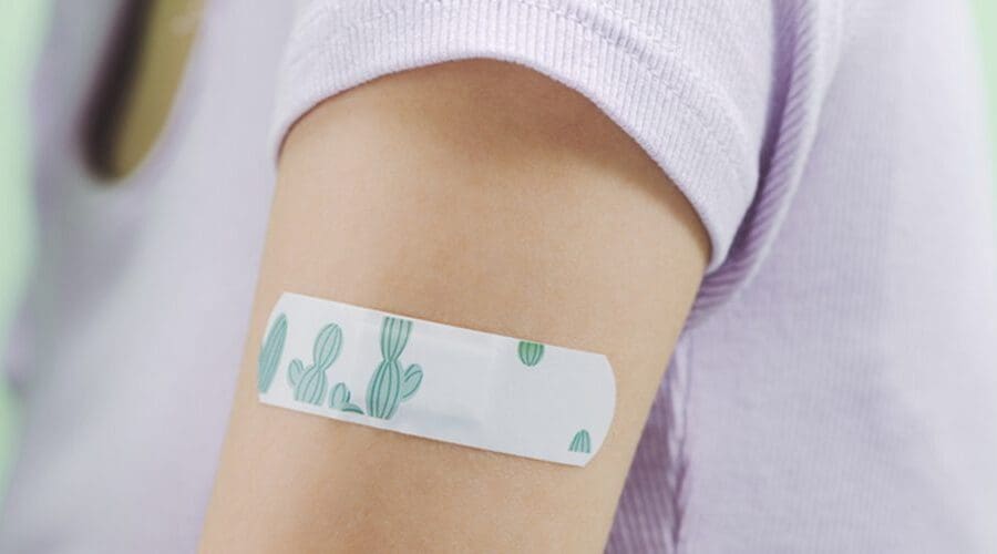 A closeup of an arm with a cactus print bandaid where a vaccine was given.