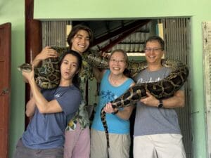 Family of four holding an enormous boa constrictor in Vietnam