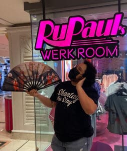 Person fanning themselves in front of RuPaul Werk Room displat